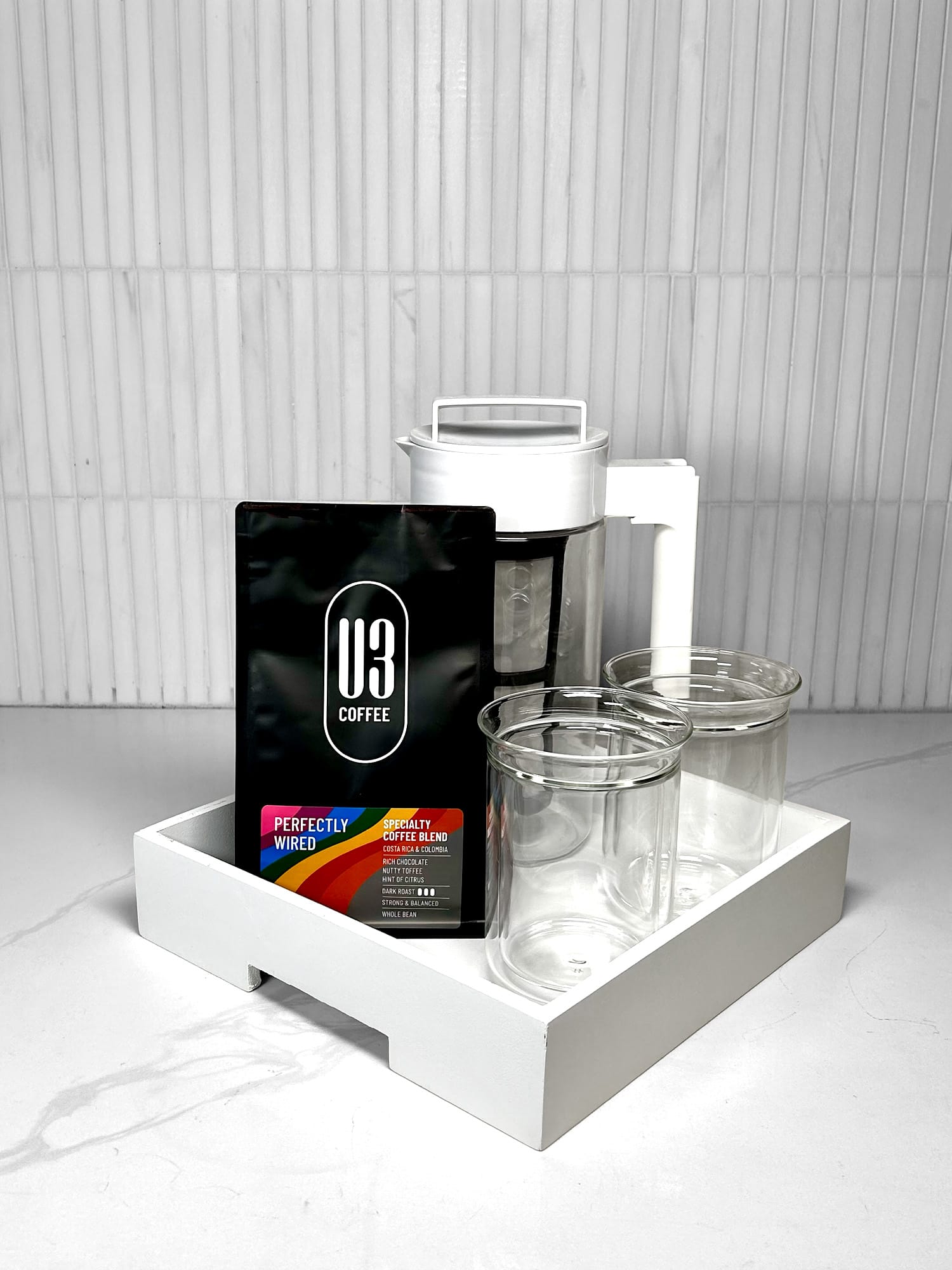 Gift Tray including 12 oz bag of U3 Perfectly Wired whole bean coffee, white Takeya cold brew coffee maker, Fellow Stagg Tasting Glasses on a white serving tray.